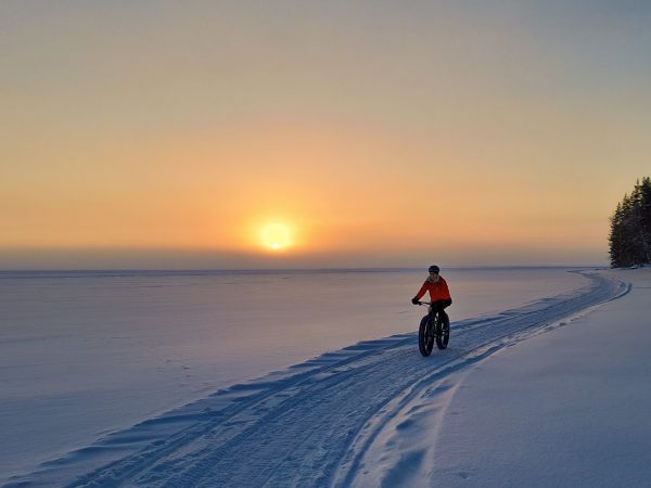 Pyöräilijä Pielisen järven jäällä ilta-auringossa