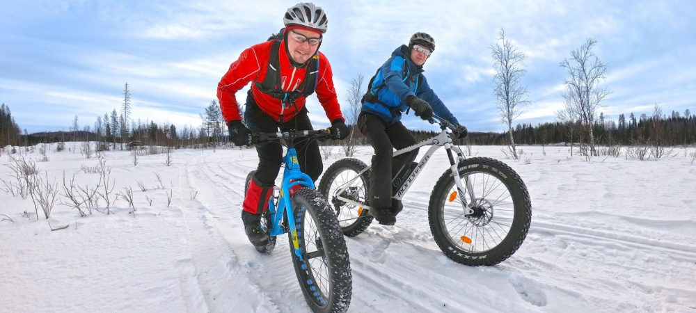 Kaksi miestä pyöräilemässä talvipolulla