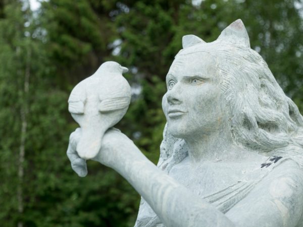 Kivinen patsas pitelee lintua kädellään