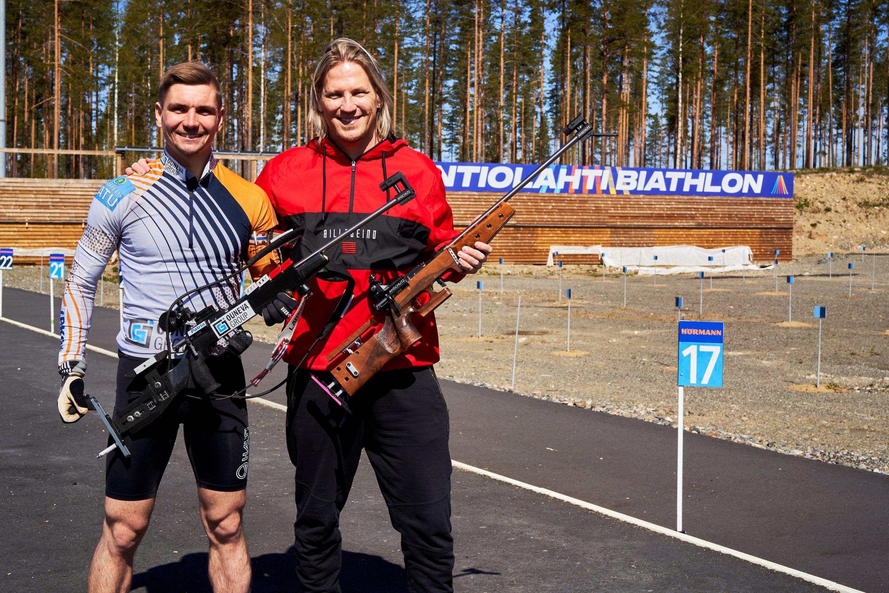 Kaksi miestä ilmakiväärien kanssa ampumahiihtostadionilla