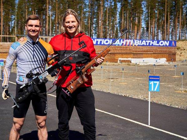 Kaksi miestä ilmakiväärien kanssa ampumahiihtostadionilla