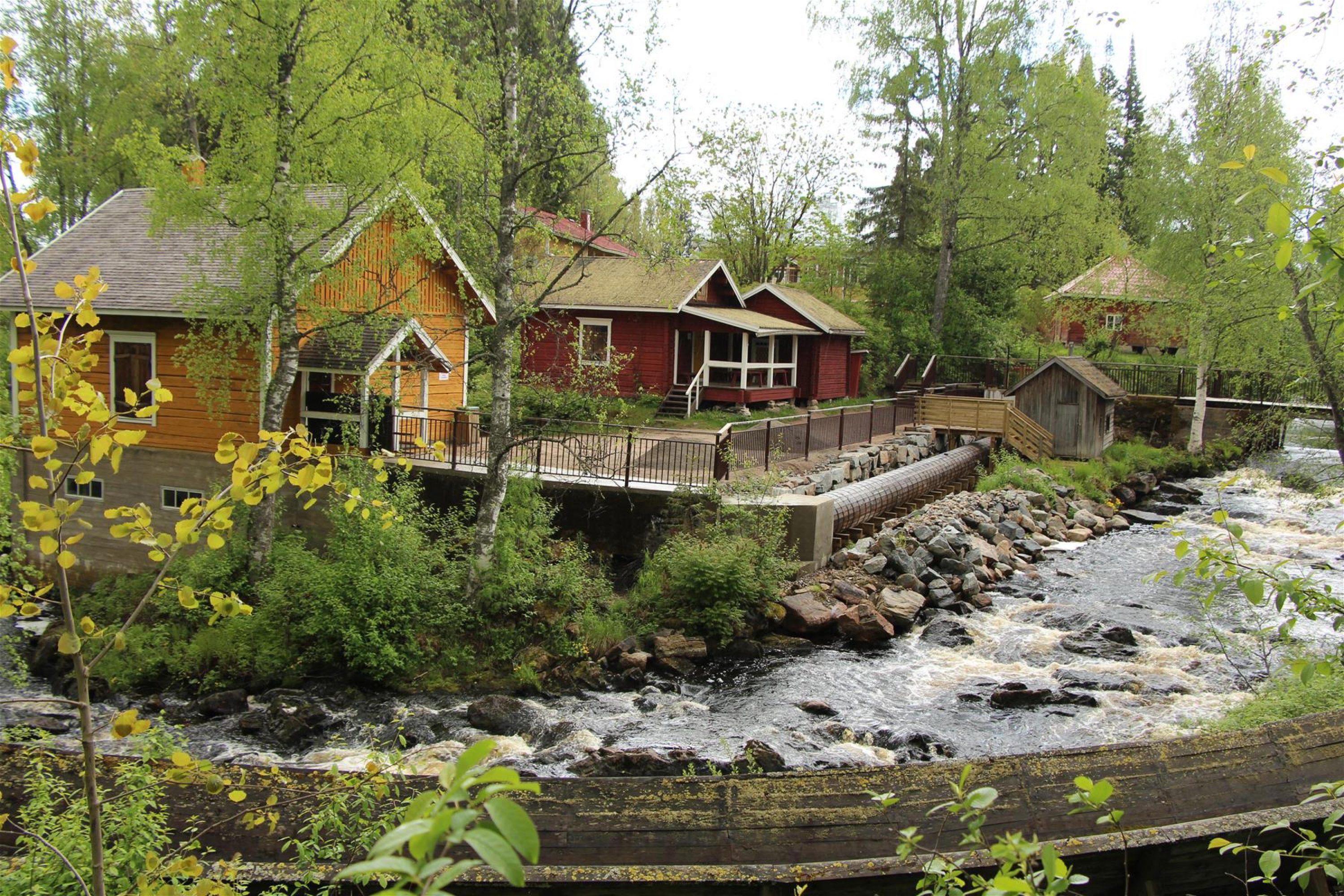 Idylliset puutalot virtaavan kosken rannalla