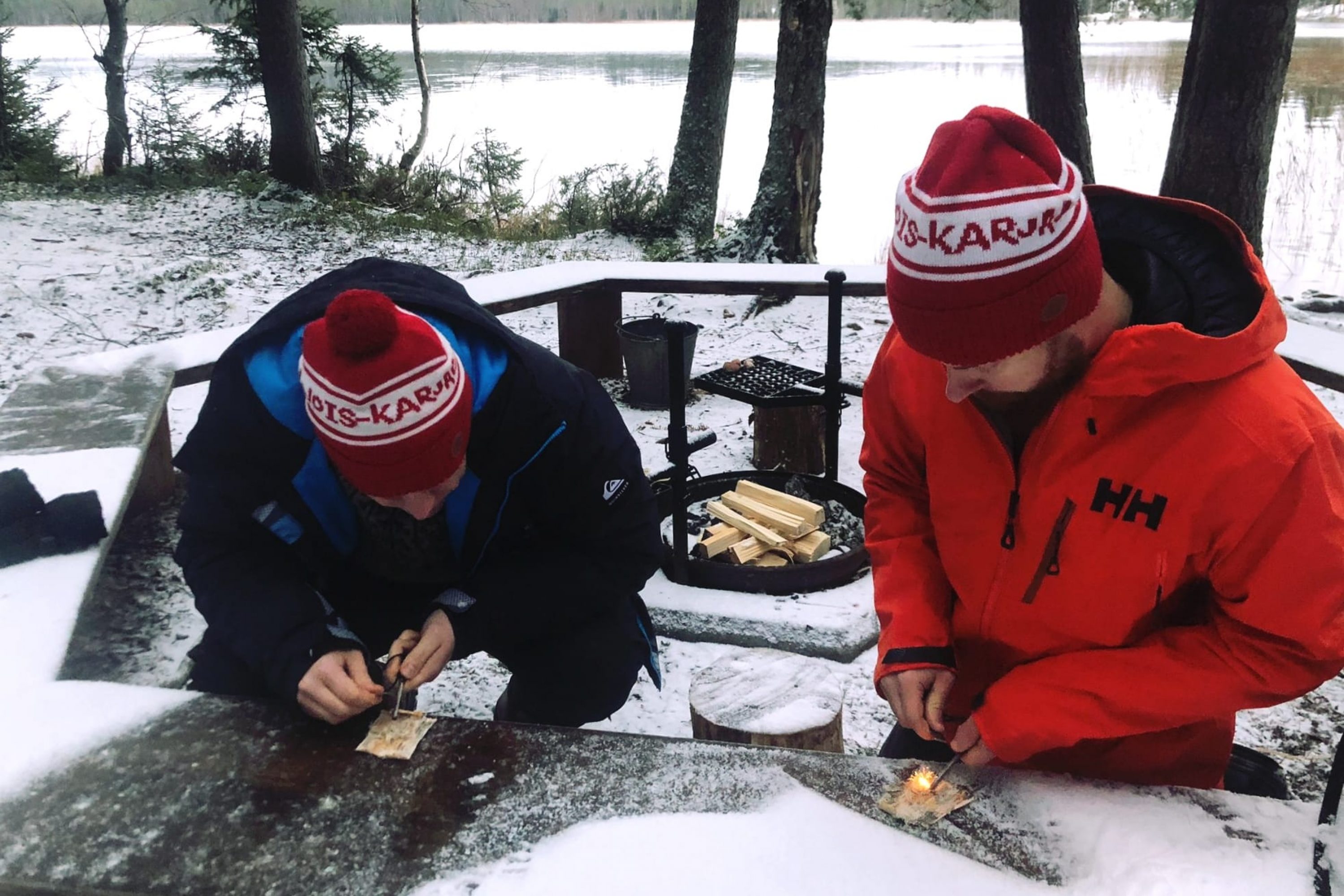 Kaksi miestä sytyttämässä nuotiota tuluksien avulla