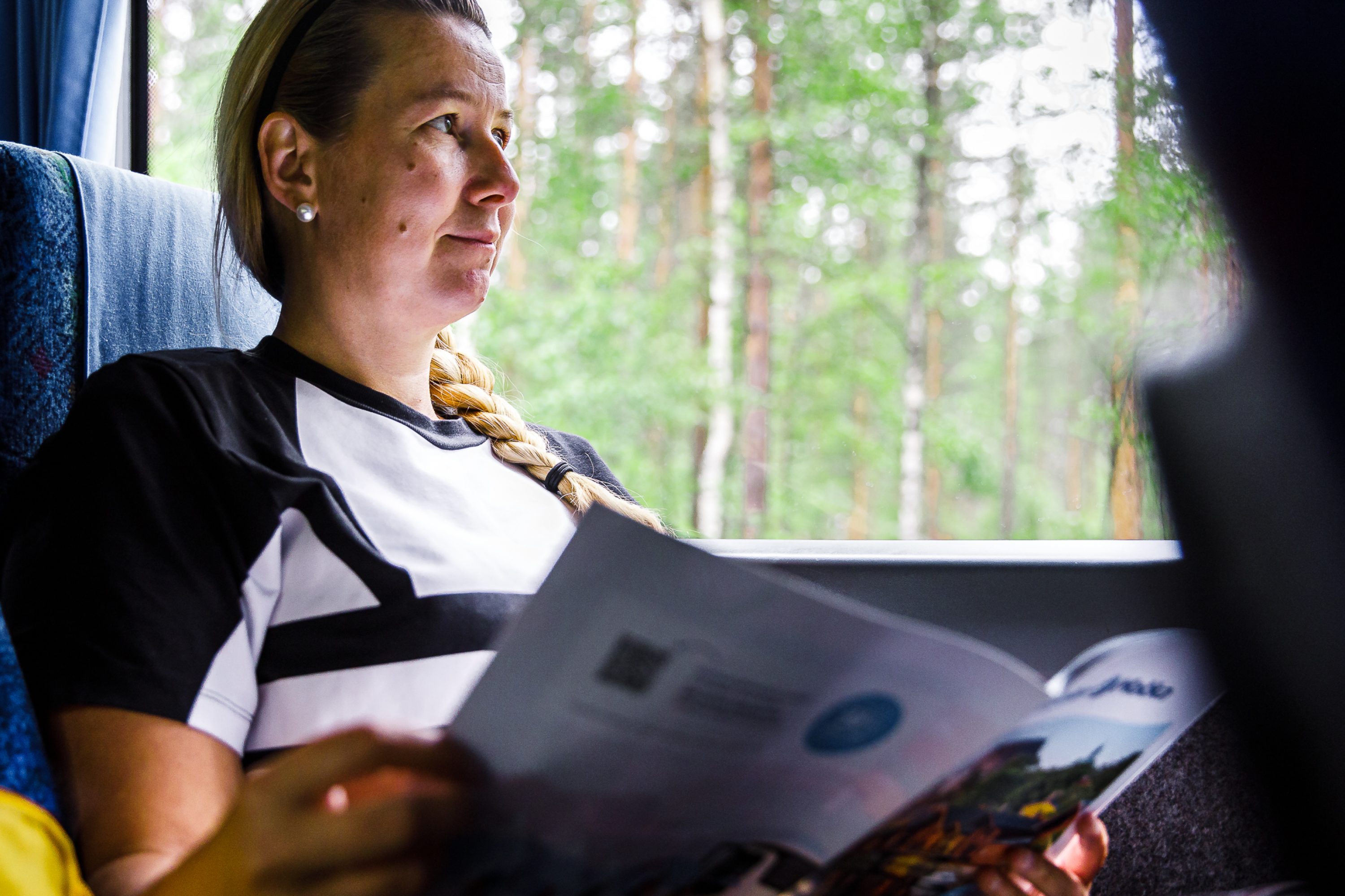A woman sits in a bus and reads newspaper