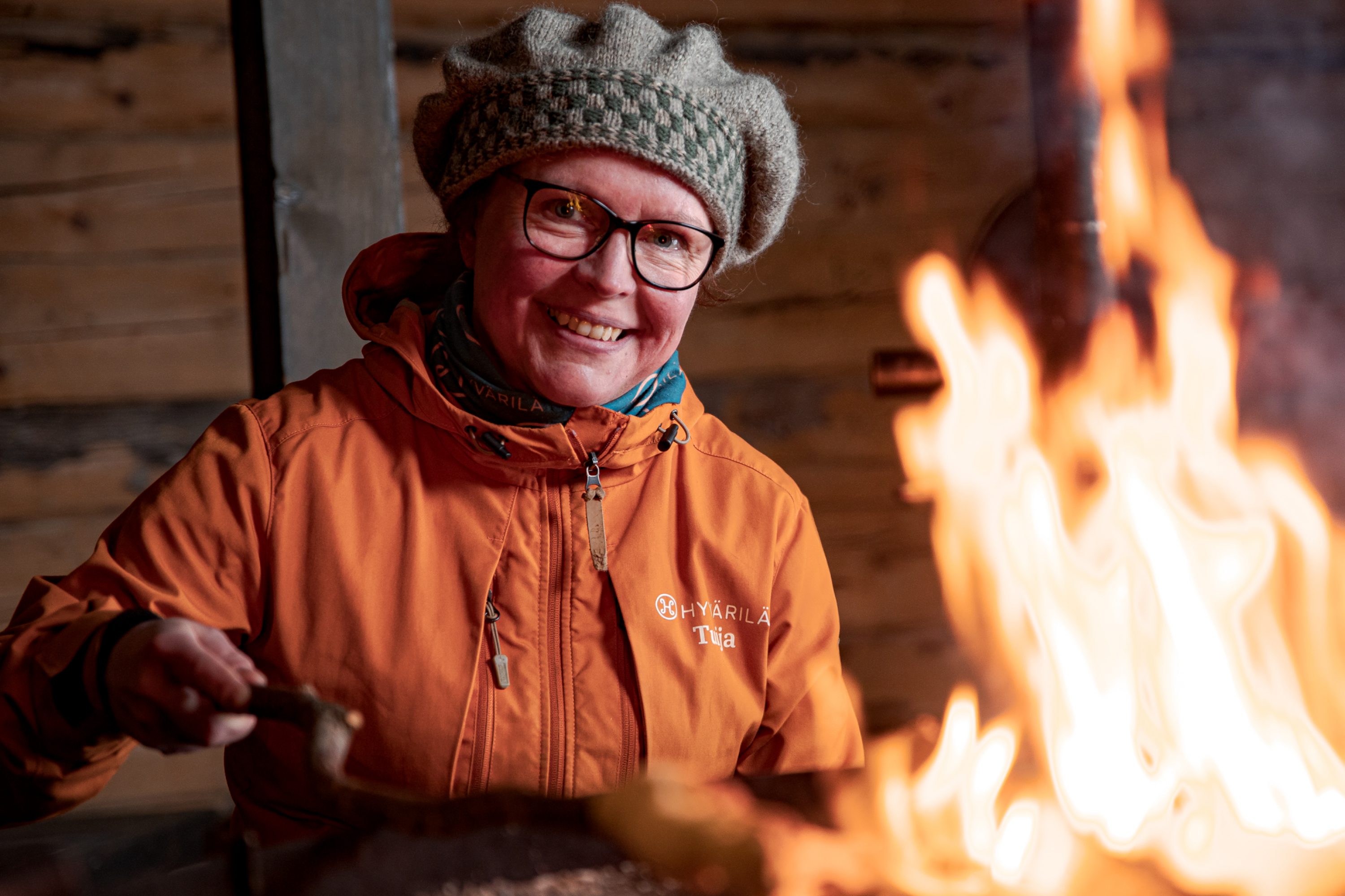 Nainen hymyilee nuotion ääressä kodassa