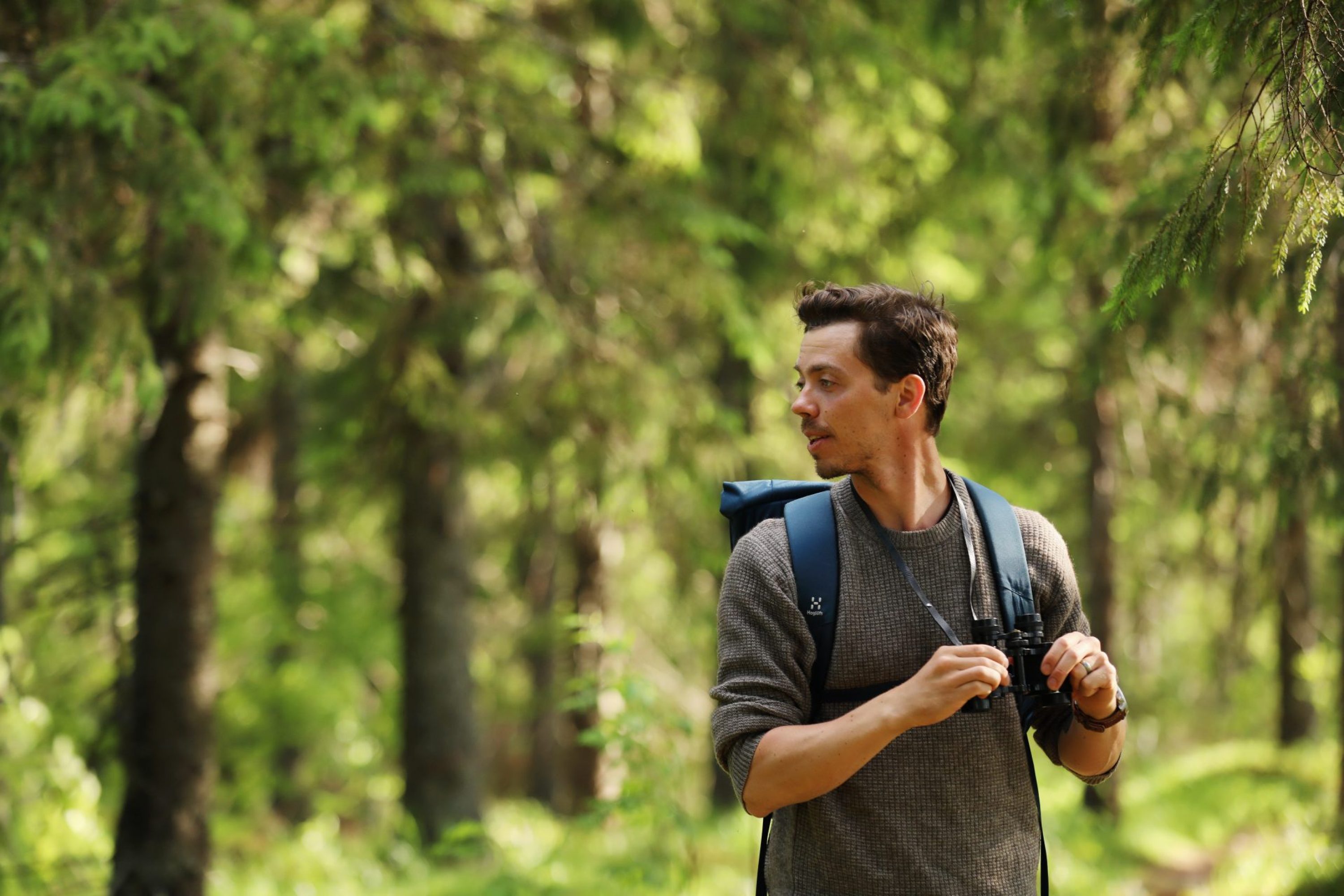 A man standing in forest with binoculars