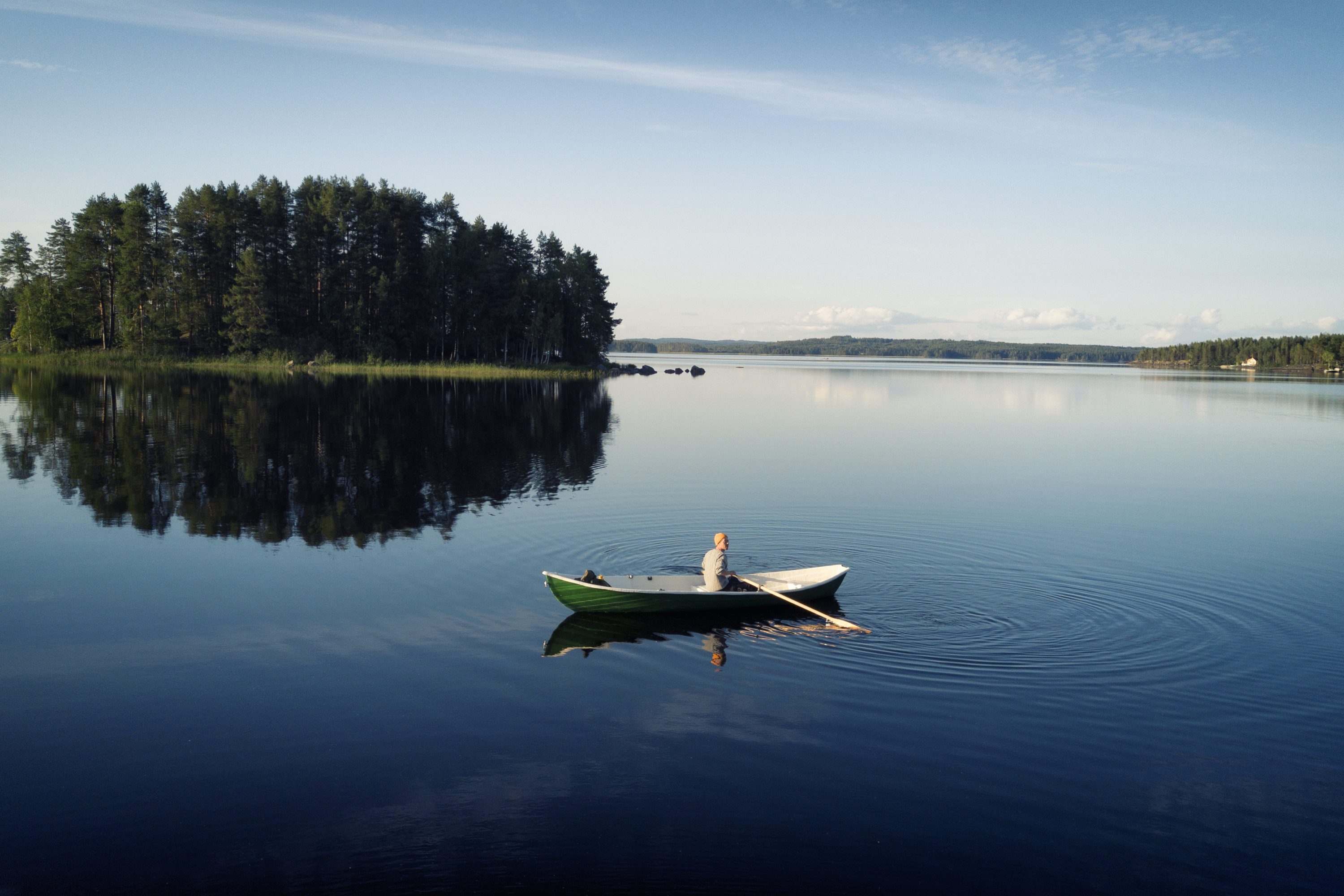 Mies soutamassa tyynellä järvellä