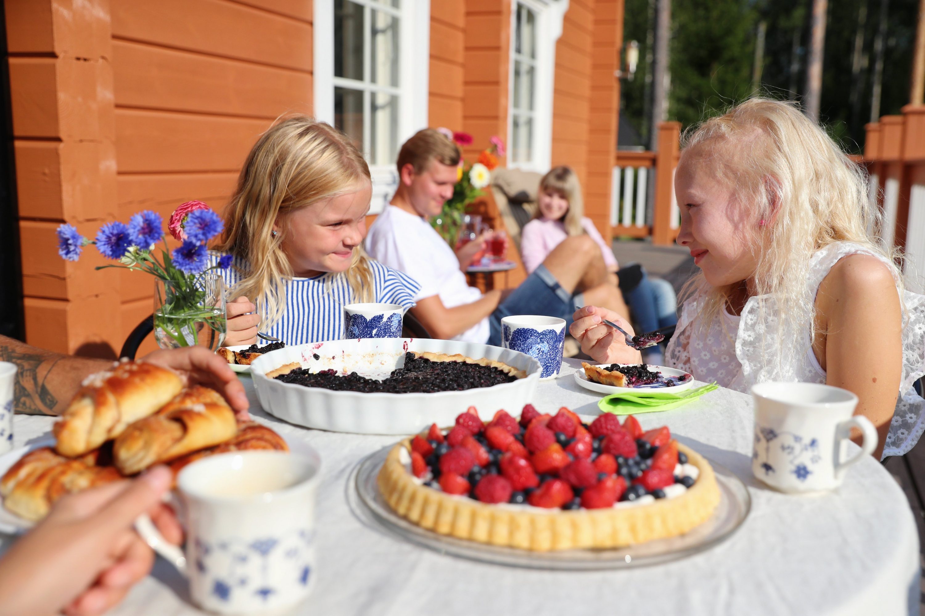 Kaksi lasta syö mustikkapiirakkaa terassilla