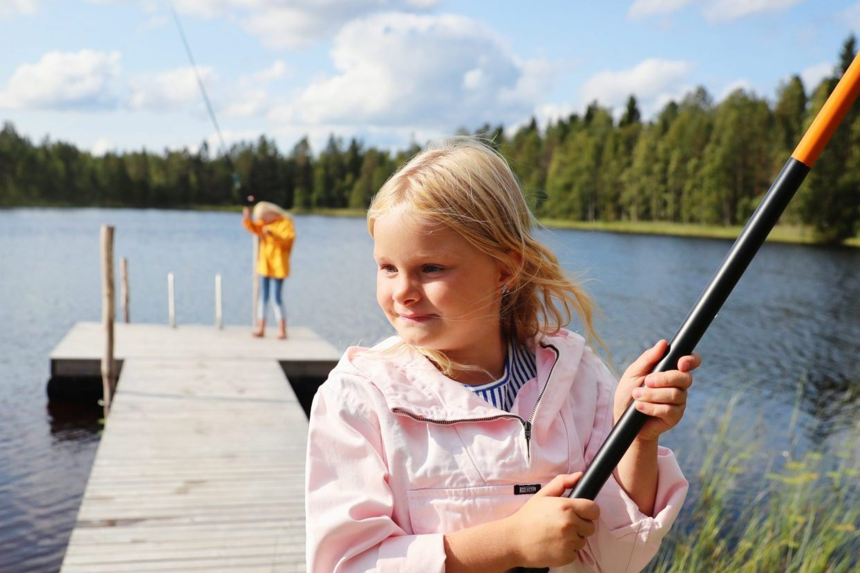 Kaksi tyttöä onkimassa laiturilla