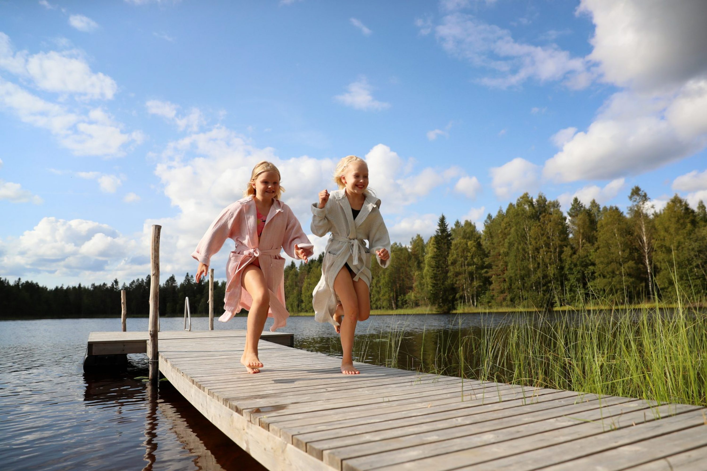 Kaksi lasta juoksee laiturilla kohti rantaa