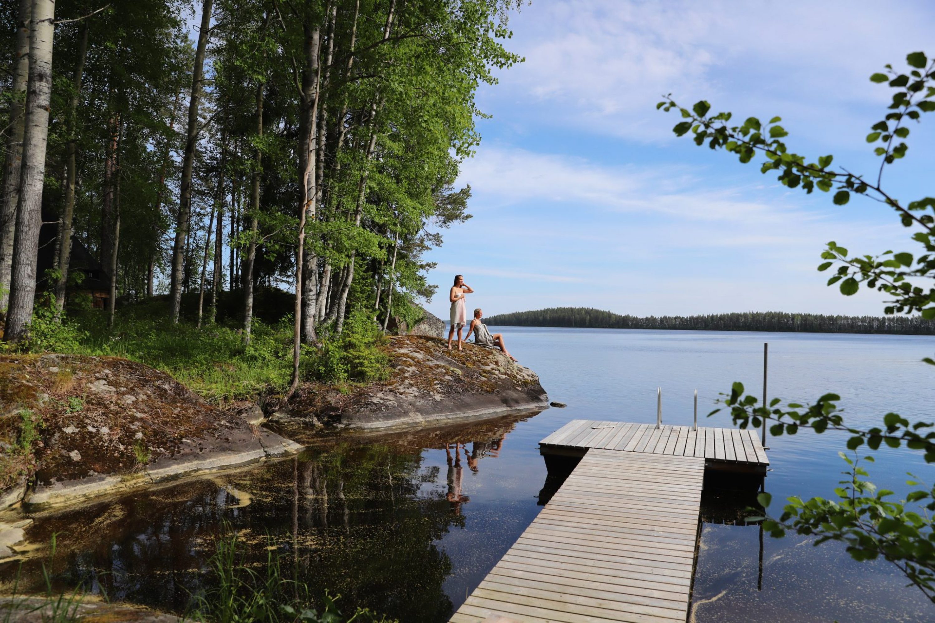 Kaksi naista pyyhkeet päällä rantakalliolla