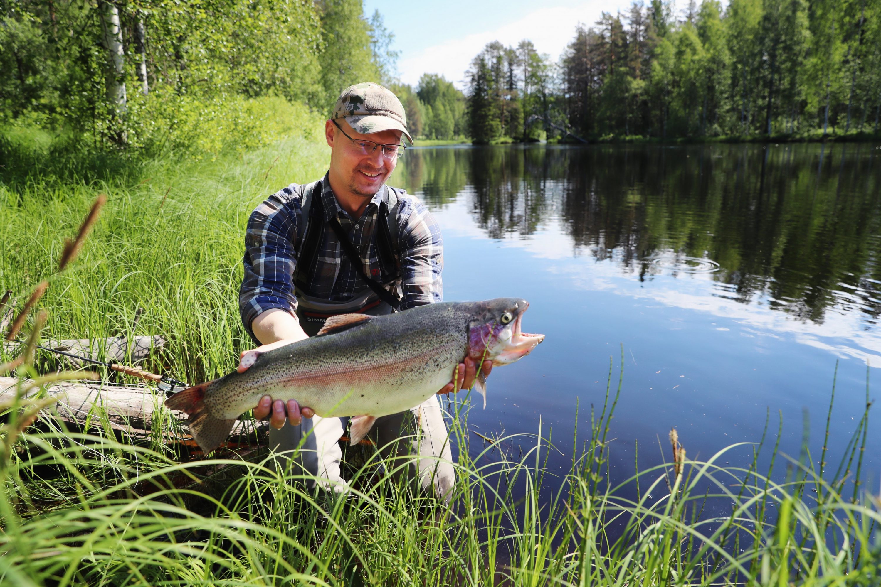 Mies pitelee isoa lohikalaa järven rannalla