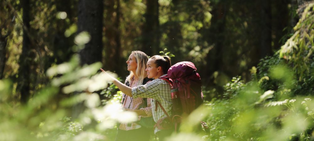 Kaksi naista retkeilemässä metsässä