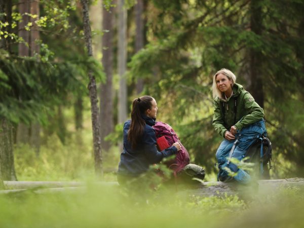 Kaksi naista rinkkojen kanssa metsässä