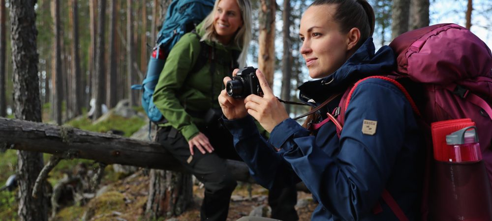 Kaksi naista ottamassa valokuvia metsässä