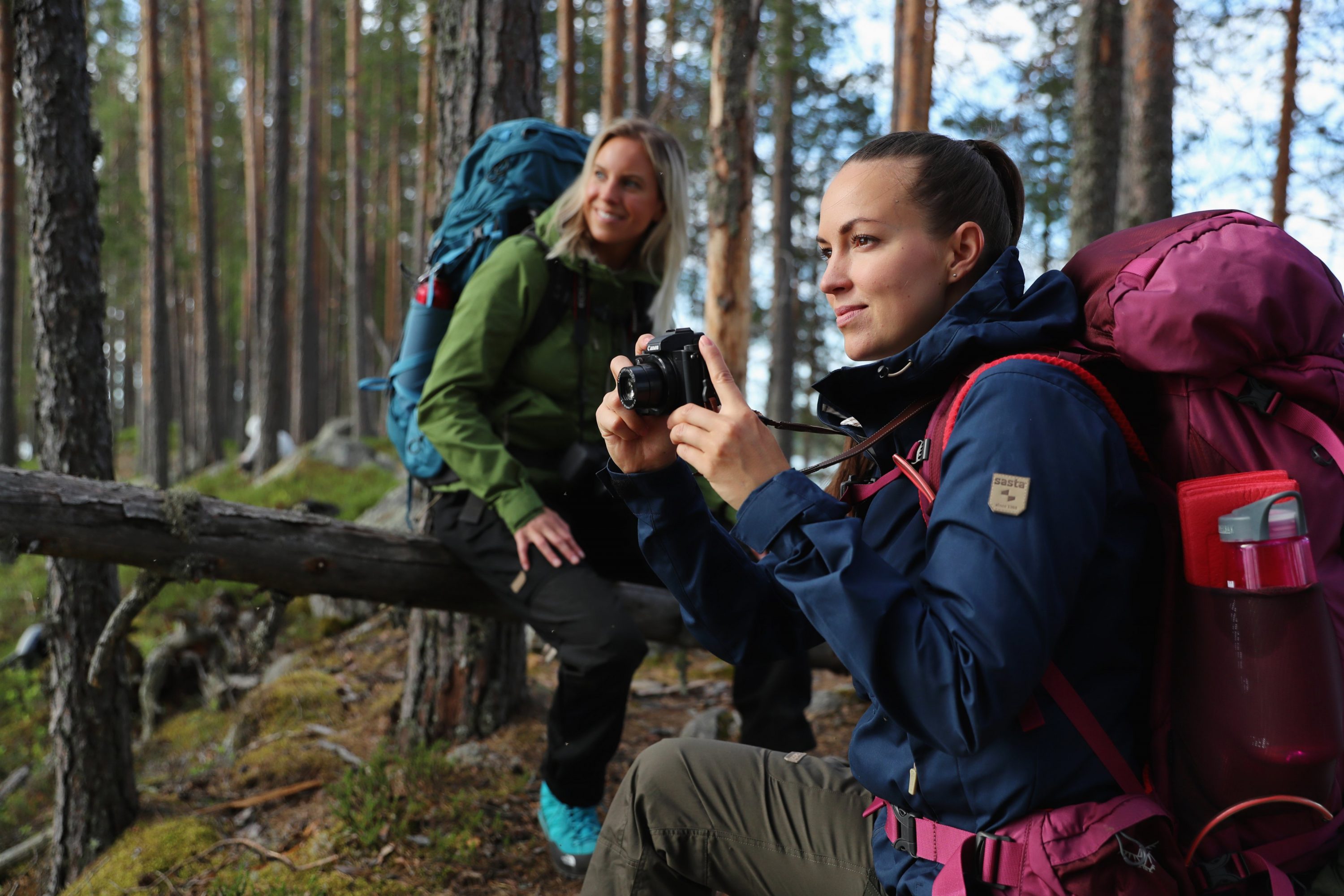 Kaksi naista ottamassa valokuvia metsässä