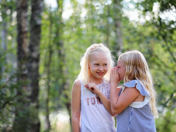 Lapset kuiskuttelevat toisilleen metsän keskellä