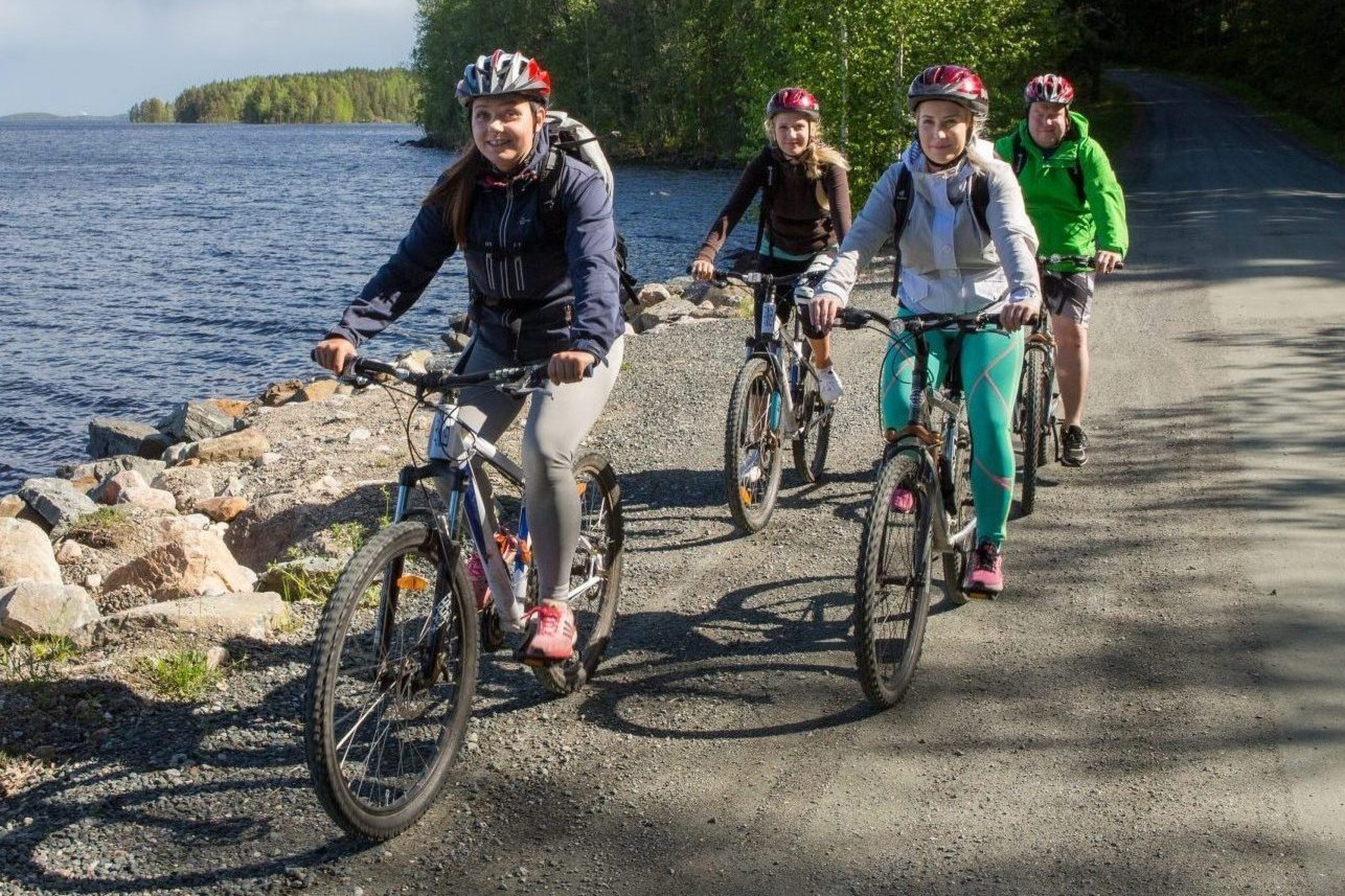 Neljä naista pyöräilee järven rannalla