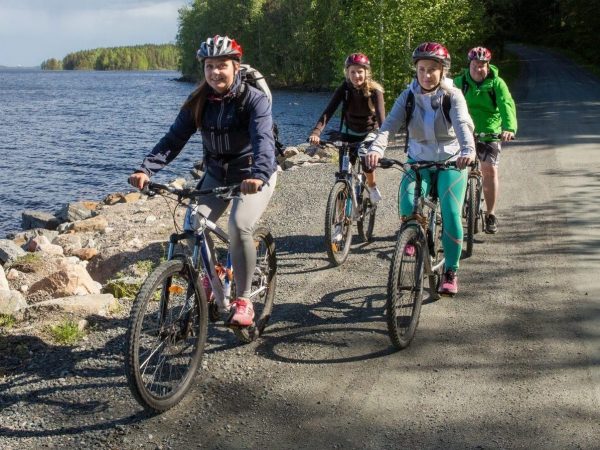 Neljä naista pyöräilee järven rannalla
