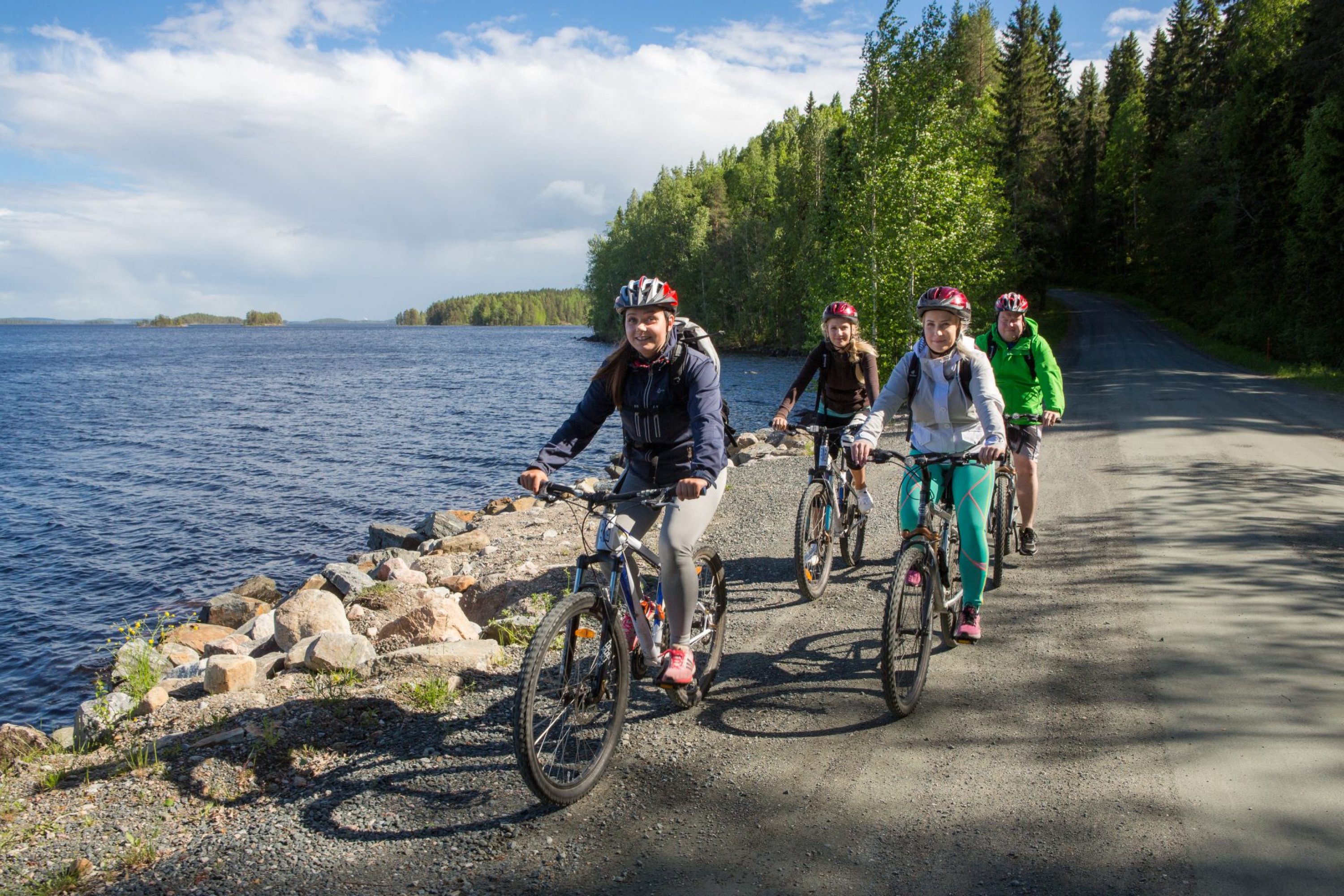 Neljä pyöräilijää järven rannalla