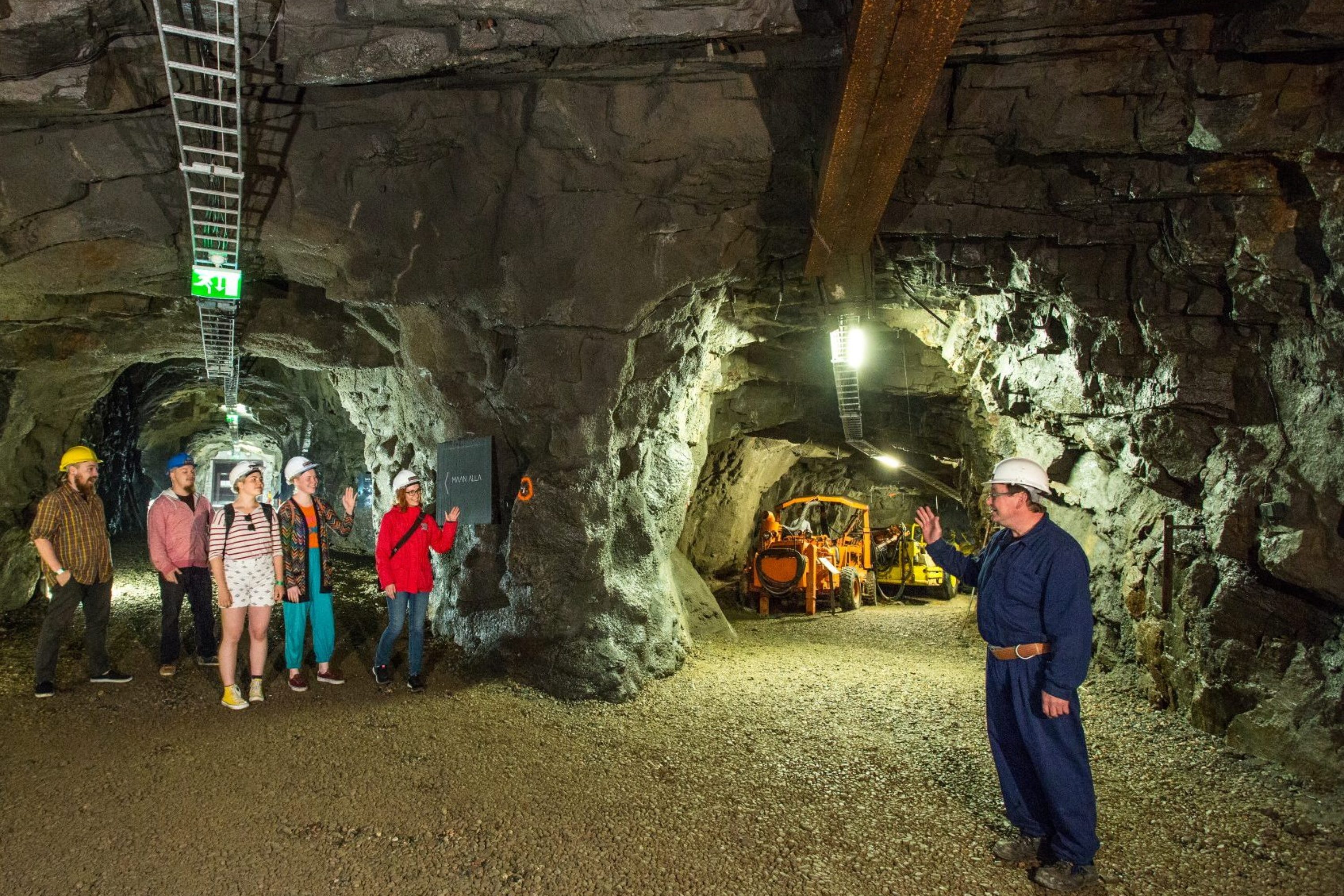 Kaivosmies ja vierailijat vanhassa kaivostunnelissa Outokummussa