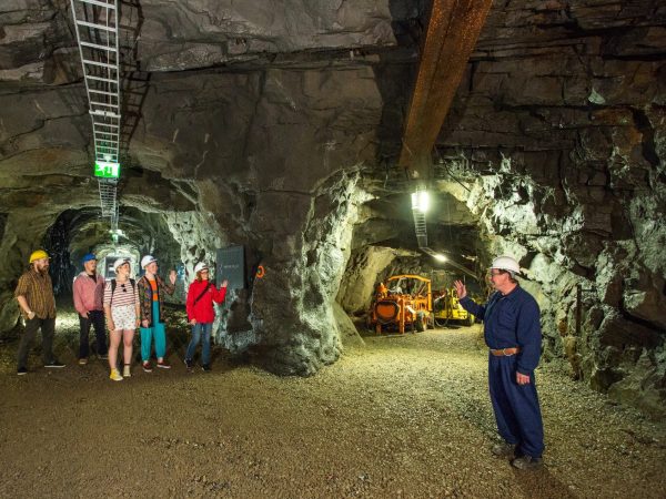 Kaivosmies ja vierailijat vanhassa kaivostunnelissa Outokummussa