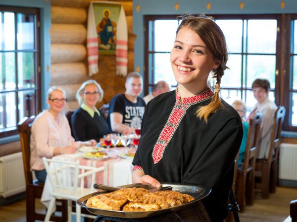 Iloinen nainen tarjoilee karjalanpiirakoita