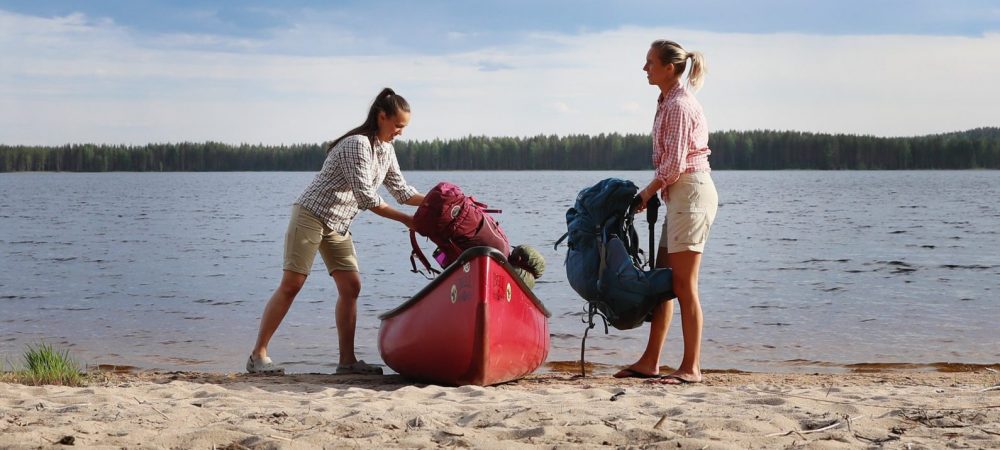 Two women taking their bags from canoe