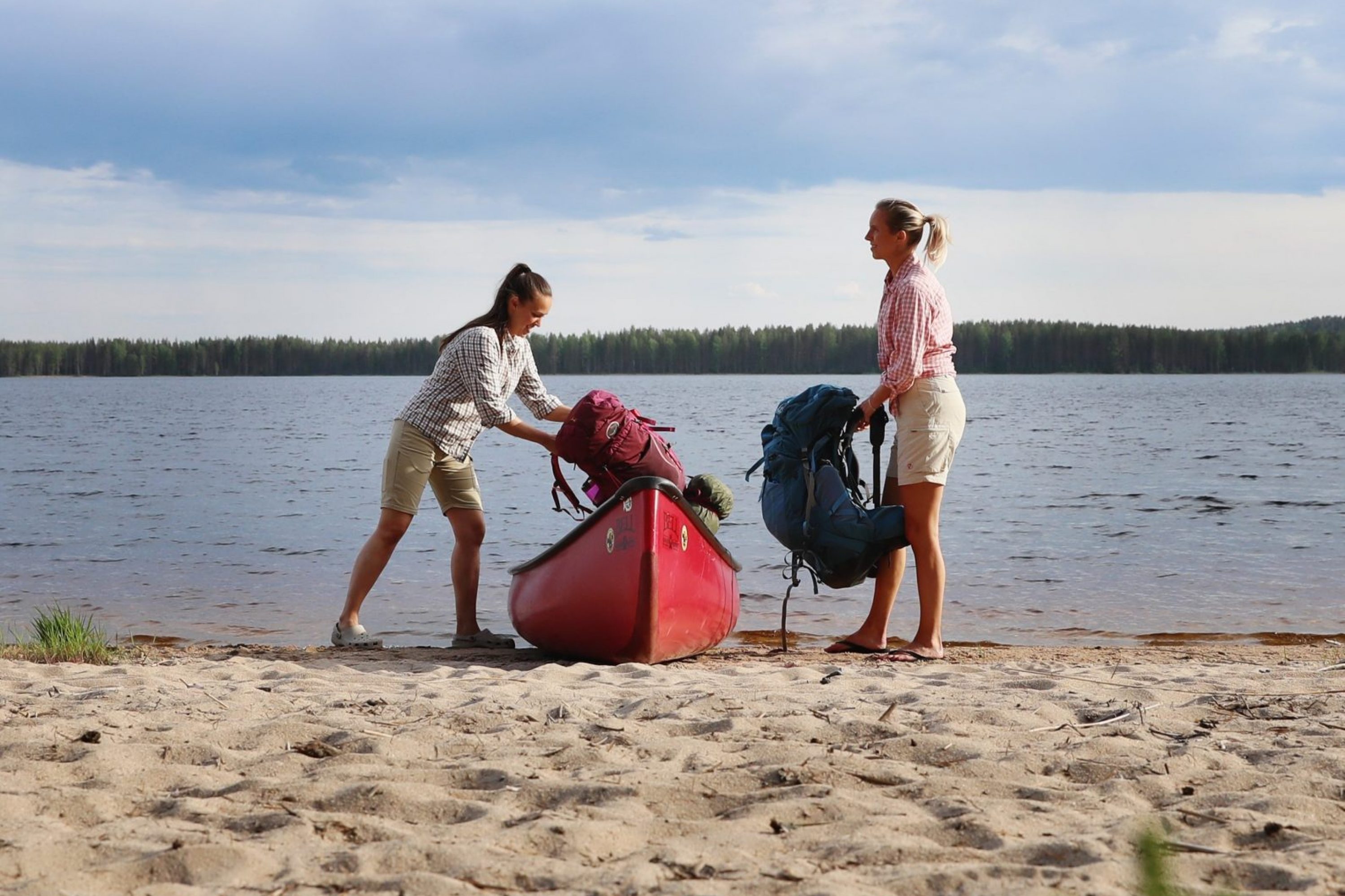 Two women taking their bags from canoe