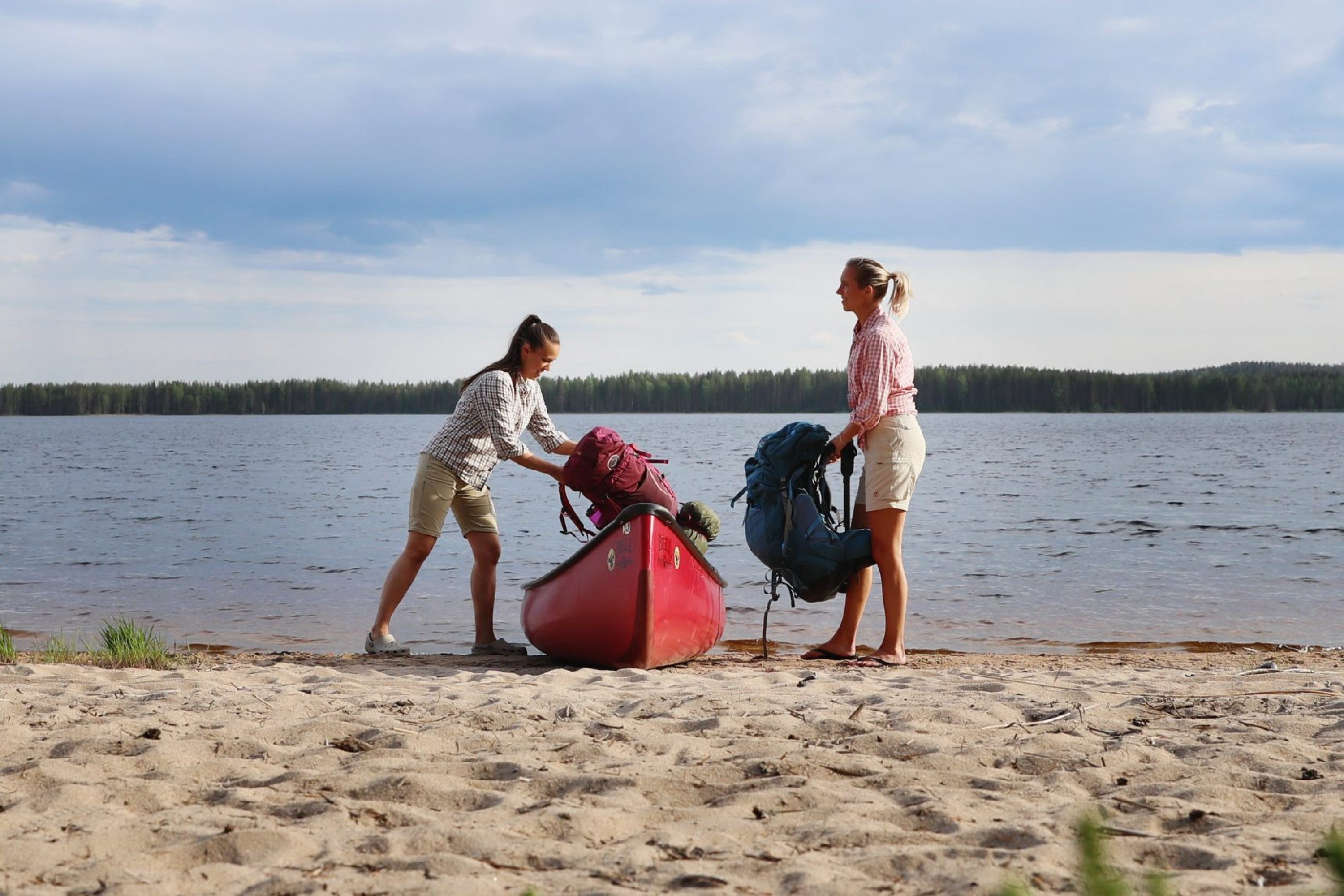 Two women taking their bags from canoe