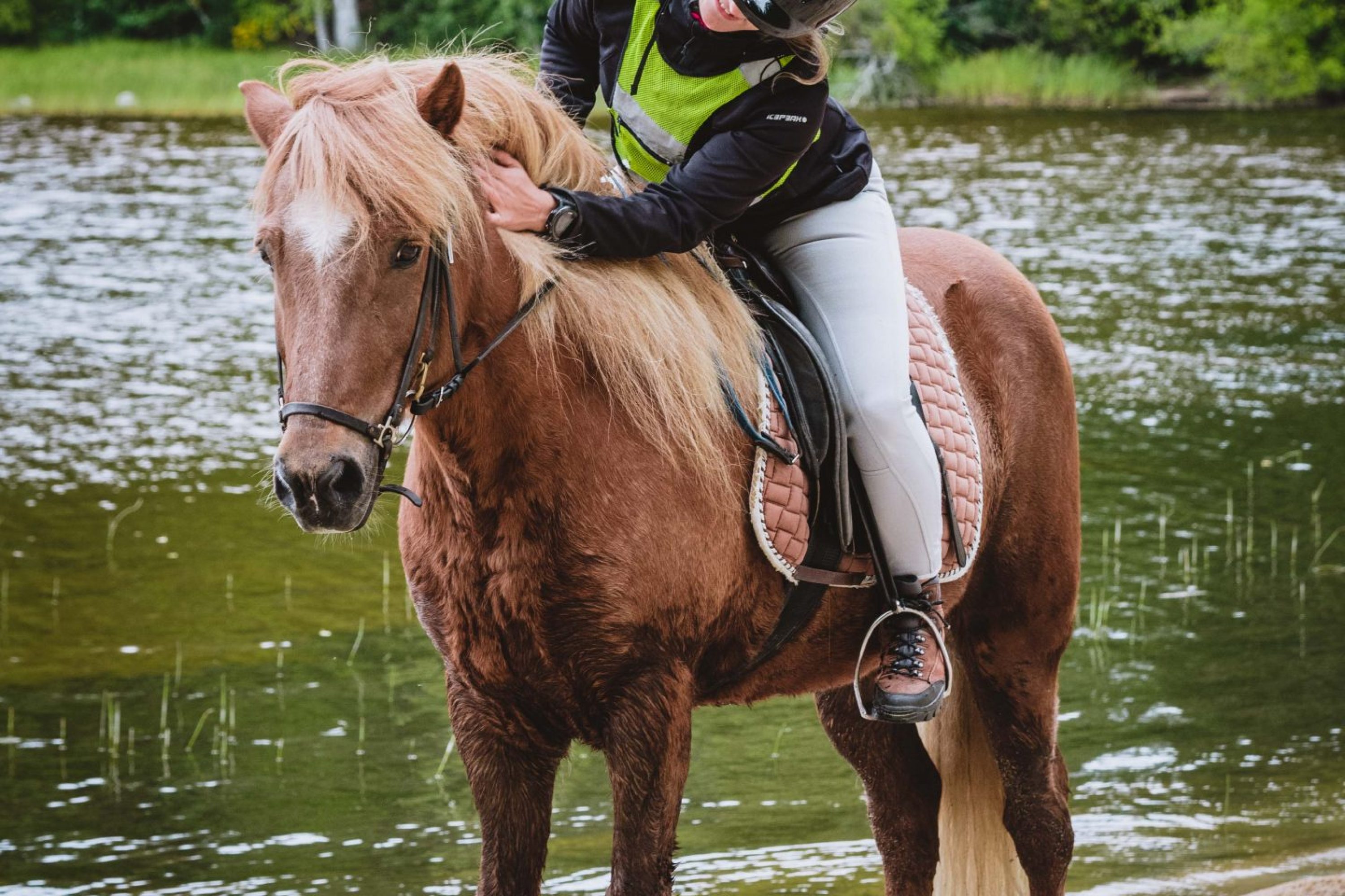 Nainen hevosen selässä rannalla